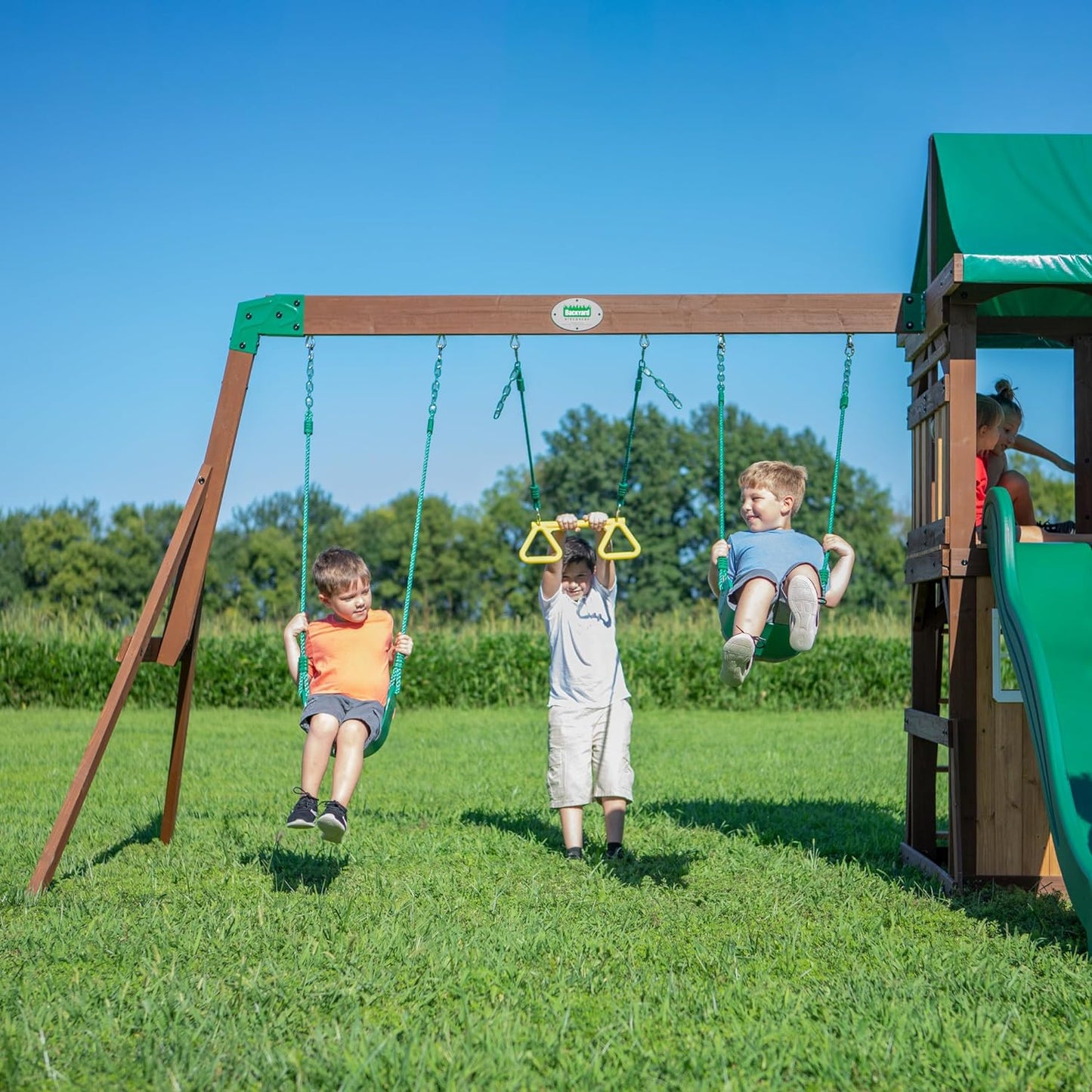 Lakewood Cedar Wood Swing Set, Covered Upper Deck with White Trim Window, Slide with Rails, Lower Fort Area with Door and Attached Bench, Swing Belts, Trapeze Bar, Stair Ladder