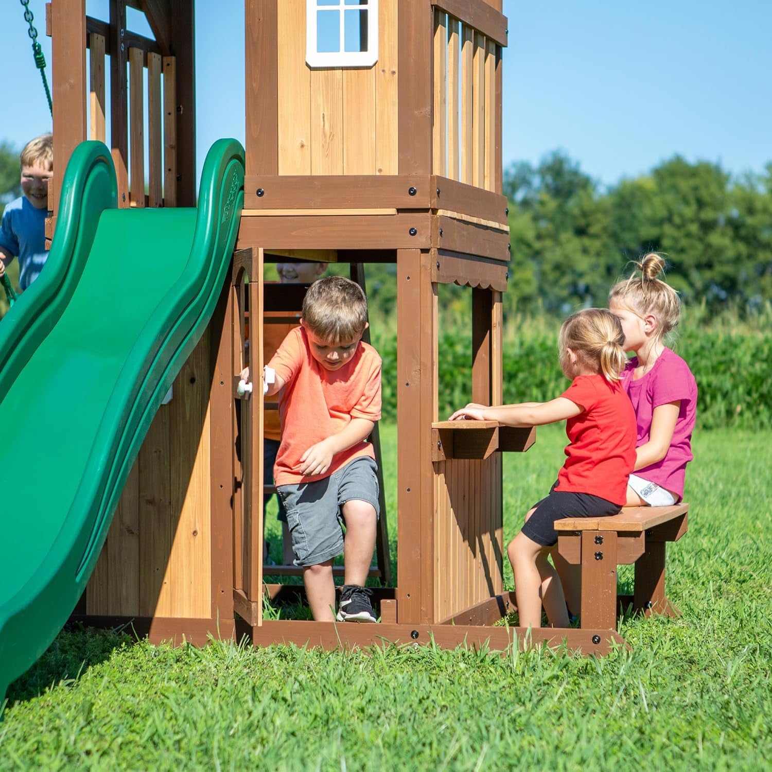 Lakewood Cedar Wood Swing Set, Covered Upper Deck with White Trim Window, Slide with Rails, Lower Fort Area with Door and Attached Bench, Swing Belts, Trapeze Bar, Stair Ladder